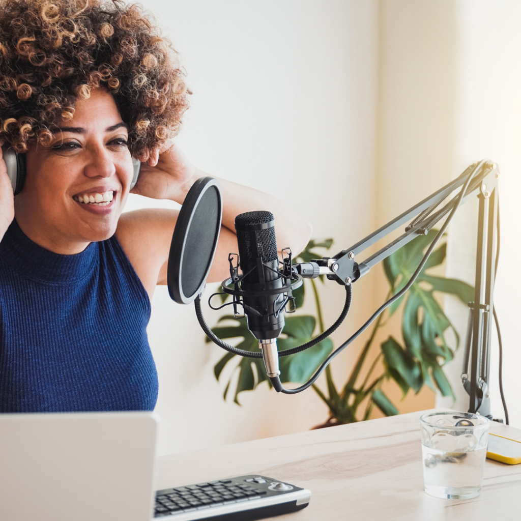 A woman hosting her podcast, confidently sharing insights and stories at her podcast station