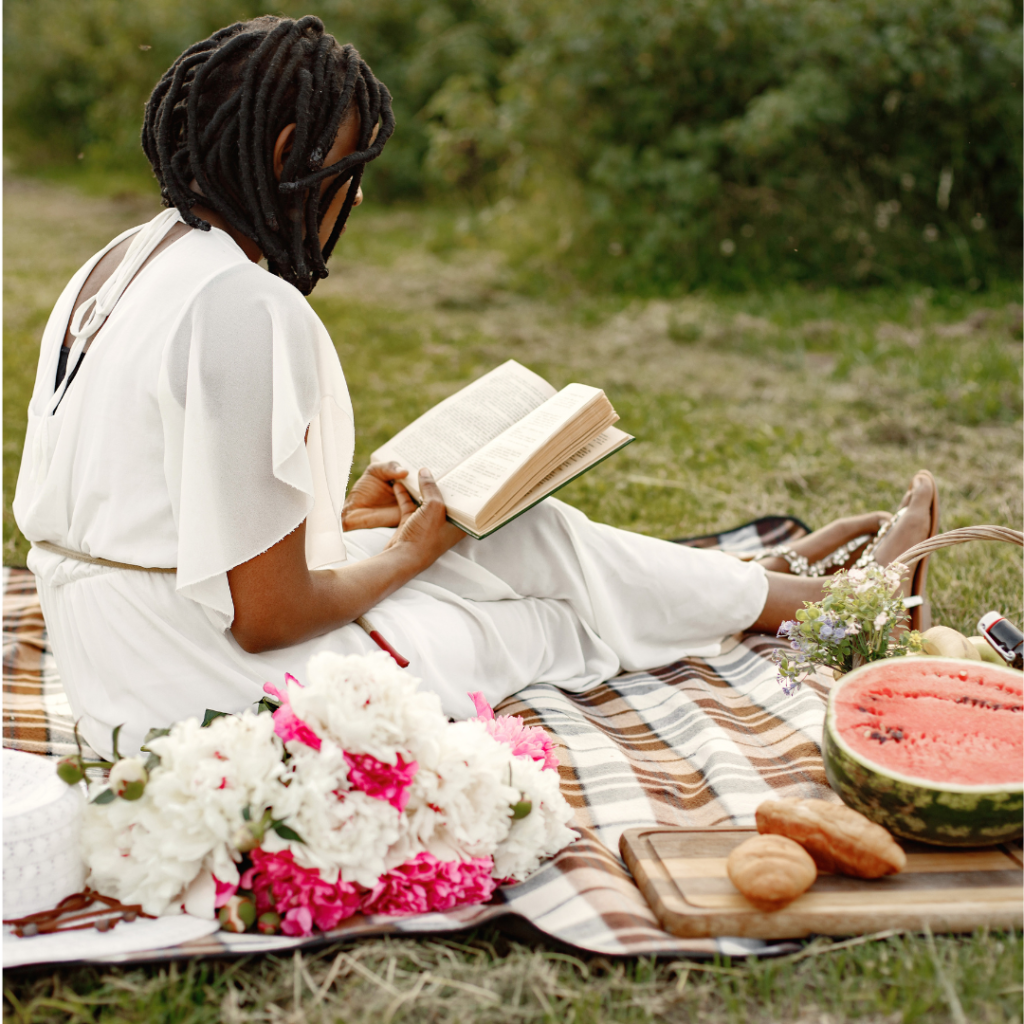 A person reading a book during a solo picnic, symbolizing self-care and the joy of dating yourself through leisurely activities in nature